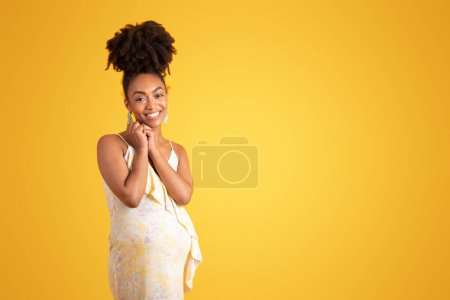 Photo for Smiling young black lady with big belly enjoys motherhood, pregnancy, isolated on yellow background, studio. Family planning, ad and offer, lifestyle, expectation of child, sale - Royalty Free Image
