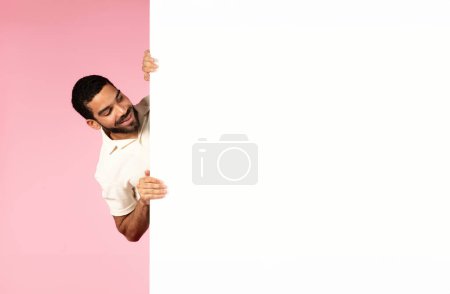 Photo for Excited curious happy young handsome bearded guy wearing casual outfit looking at huge white empty placard mockup blank space for advertisement, pink background. Summer deal - Royalty Free Image