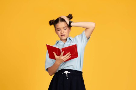 Photo for Tired unhappy teen european girl reads book, presses hand to head, isolated on yellow studio background. Problems with study, education at school, homework prepare for test emotions - Royalty Free Image