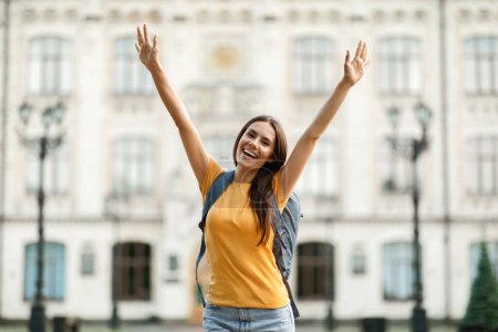 Photo for Successful Student. Joyful College Female Raising Arms And Celebrating Success Outdoors After Getting Tuition And Educational Grant For Learning Abroad, Posing With Backpack Near University Outside - Royalty Free Image
