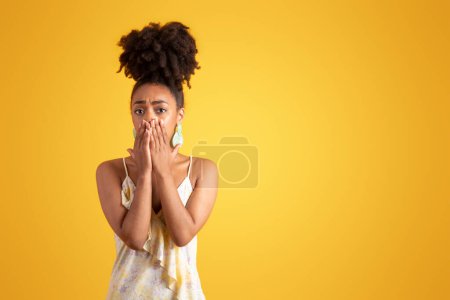 Photo for Shocked frightened young black woman in dress covering mouth with hands, isolated on yellow background, studio. Fear reaction, bad news, facial expression and stress, human emotions - Royalty Free Image