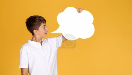 Téléchargez les photos : Joyeux garçon européen adolescent regarder nuage abstrait, bulle de mots et de pensées, isolé sur fond de studio jaune. Annonce, offre, enfance et études, éducation à l'école, vente - en image libre de droit