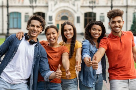 Photo for We Like Learning. Multiethnic Students Gesturing Thumbs Up While Standing Outdoors, Group Of University Friends Recommending Educational Or Tuition Program, Enjoying Study, Smiling To Camera - Royalty Free Image