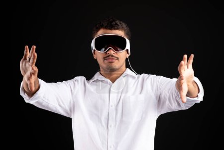 Photo for Entertainment in virtual world. Brazilian man in vision pro vr glasses playing modern game and gesturing hands, isolated on black background, studio shot - Royalty Free Image