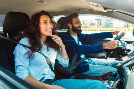 Téléchargez les photos : Homme et femme arabe excités assis dans leur nouvelle voiture, regardant la route et souriant, faire un essai routier dans la ville, les conjoints du Moyen-Orient partent en vacances d'été en voiture - en image libre de droit
