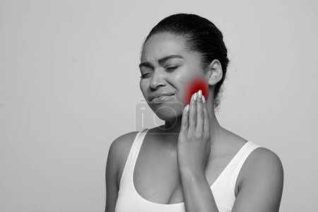 Photo for Black and white photo of young african american lady suffering from tooth pain, black woman touching sore red zone on her cheek, isolated on studio background, copy space - Royalty Free Image