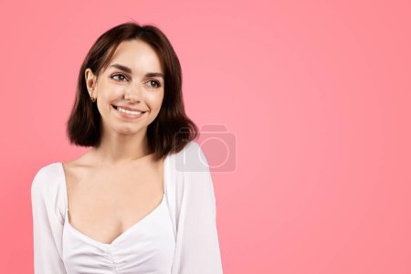 Photo for Cheerful millennial caucasian brunette woman looking at empty space, isolated on pink background, studio. Beauty care, freshness, lifestyle, ad and offer, sale, facial expression - Royalty Free Image