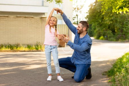 Photo for Father-daughter waltz. Happy loving dad and his child girl dancing outdoors while walking in park and enjoying spending free time together on weekend - Royalty Free Image