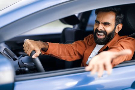 Photo for Traffic Issue. Angry Middle Eastern Driver Man Shouting Driving Car, Gesturing From Opened Automobile Window, Having Conflict On Road During Auto Ride In City, Side View Portrait, Selective Focus - Royalty Free Image