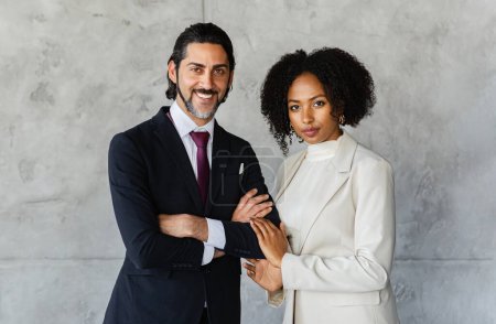 Téléchargez les photos : Portrait de gens d'affaires multiethniques posant au bureau sur un mur de marbre gris vide, joyeux jolie jeune femme noire et l'équipe de gestion de l'homme du Moyen-Orient debout ensemble et souriant - en image libre de droit