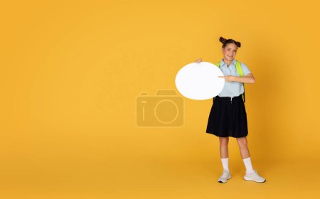 Photo for Smiling caucasian teenager girl point finger to abstract cloud with copy space for ad and offer, isolated on orange studio background. Study recommendation, school education advice, full length - Royalty Free Image
