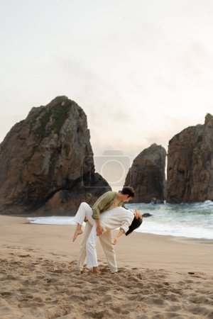 Téléchargez les photos : Couple amoureux romantique dansant sur la plage, profitant de leur date sur le bord de l'océan, espace libre, pleine longueur, plan vertical. Guy et dame amoureux marchant et passant du temps ensemble sur le littoral - en image libre de droit