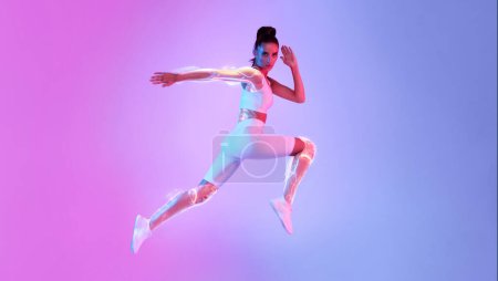 Téléchargez les photos : Femme athlétique sautant posant en plein air regardant la caméra s'exerçant sur fond rose et bleu néon en studio. Pleine longueur, Panorama avec espace vide. Concept sportif et technologique. Technique sportive - en image libre de droit