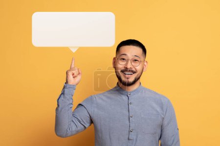 Photo for Business Idea Concept. Excited Young Asian Man Pointing Finger Up At White Blank Speech Balloon, Happy Millennial Guy Found Problem Solution, Having Inspiration Moment, Posing On Yellow Background - Royalty Free Image