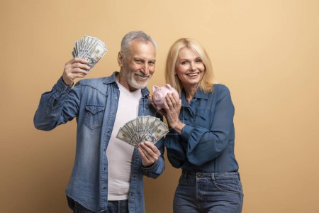 Photo for Wealthy rich happy elderly man and woman beautiful retired couple posing with money dollar banknotes and piggy bank isolated on beige background, showing their savings, deposit cash, copy space - Royalty Free Image