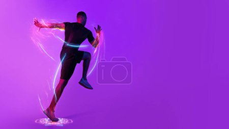 Photo for Digital sport, sports technology concept. Motivated black sportsman exercising on purple background in neon light, running or jumping towards copy space, hologram over athlete body, panorama - Royalty Free Image