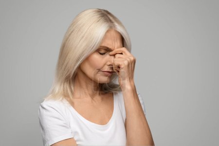 Photo for Depression Concept. Portrait Of Upset Mature Female Touching Head In Despair, Senior Woman Rubbing Nosebridge And Frowning, Suffering Headache Or Mental Problems, Standing On Grey Studio Background - Royalty Free Image