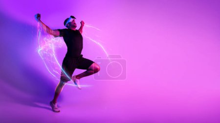 Photo for Emotional black sportsman jumping in the air and raising hands up celebrating success sports record, exercising with VR goggles over pink and purple background, panorama, copy space. Sports techs - Royalty Free Image