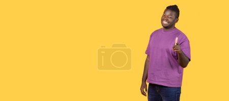 Téléchargez les photos : Je te choisis. Portrait de l'homme afro-américain heureux pointant index et clin d'oeil à la caméra, posant sur fond jaune. Celui qui fait le choix et indique le geste. Panorama, espace libre - en image libre de droit