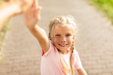 Photo for Pretty smiling schoolgirl giving high five while walking and riding bike in park, closeup. Active leisure, hobby and pastime, physical activity outdoors - Royalty Free Image