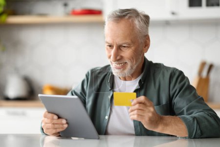 Photo for Happy Elderly Man With Digital Tablet And Credit Card In Hands Posing In Kitchen Interior, Cheerful Senior Gentleman Making Online Payments, Shopping In Internet With Modern Gadget, Closeup Shot - Royalty Free Image