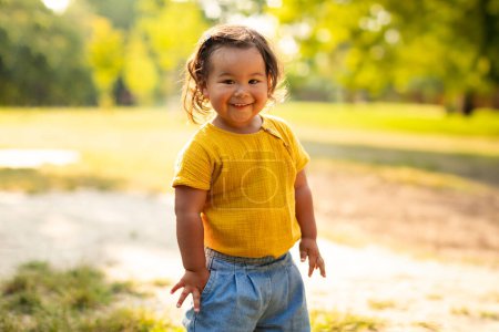Photo for Toddlers Joyful Summer Adventures. Cheerful Korean Little Baby Girl Enjoying Outdoor Playtime, Standing Alone At Countryside, Delighting in Exploration Outside Amidst the Beauty of Nature - Royalty Free Image