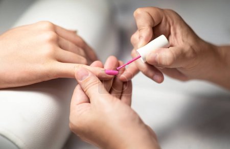 Photo for Manicurist Woman Applying Acrylic Pink Gel Polish On Clients Fingernails, Closeup Of Hands. Unrecognizable Lady Doing Professional Manicure At Modern Nail Beauty Studio. Cropped, Selective Focus - Royalty Free Image