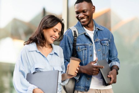 Photo for Happy young multiracial couple walking by street, talking and laughing. Cheerful students black man and caucasian woman in love have date after university college lessons, enjoying time together - Royalty Free Image