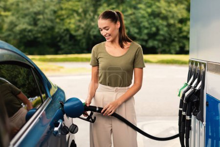 Lächelnde Frau tankt an der modernen Tankstelle im Freien Auto mit Biokraftstoff und genießt das Betanken. Umweltfreundliche und komfortable Autopflege, Automobil-Betankungskonzept
