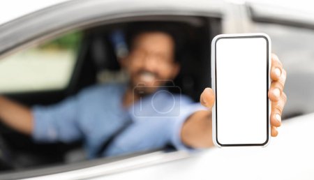 Téléchargez les photos : Homme conducteur assis dans une belle voiture, montrant téléphone portable avec écran blanc vierge, recommandant la plus récente application mobile pour la navigation, maquette, panorama. Voiture, automobile, conduite et technologies modernes - en image libre de droit