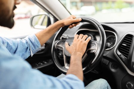 Photo for Cropped shot of middle eastern man honking while driving, sitting in car. Selective focus on steering wheel. Closeup of driver beeping the horn in auto. Transportation and traffic concept - Royalty Free Image