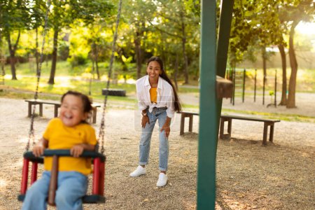 Photo for Happy Motherhood. Joyful Asian Mother Swinging Her Toddler Baby Daughter on a Park Swing Outside, Bonding And Enjoying Playtime Moments On Weekend. Selective Focus on Positive Casual Mommy - Royalty Free Image
