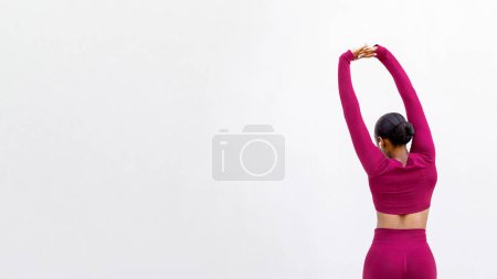 Téléchargez les photos : Vue arrière de dame noire athlétique avec un beau corps bien ajusté portant des vêtements de sport serrés roses étirant les bras sur fond blanc blanc, panorama avec espace de copie. Fitness, Pilates, Entraînement, Sport - en image libre de droit
