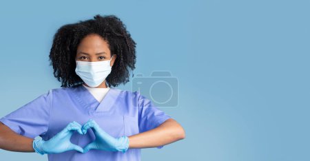 Photo for Glad black millennial lady nurse in uniform, protective mask, gloves making heart sign with hands, isolated on blue studio background. Help and love gesture, support, work, medicine and health care - Royalty Free Image