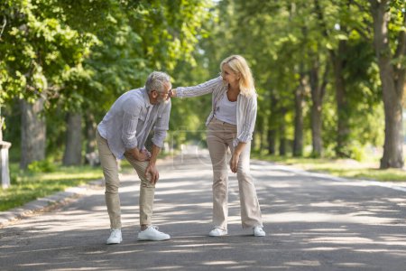 Photo for Mature Man Suffering Knee Injury While Walking In Park With Wife, Upset Senior Manle Having Osteoarthritis, Standing On Path And Rubbing Painful Area, Caring Woman Supporting Husband, Copy Space - Royalty Free Image