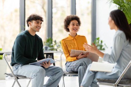 Photo for College collaboration. Cheerful multiracial students talking and discussing their educational project together, sitting in classroom on chairs - Royalty Free Image