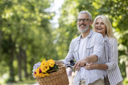 Téléchargez les photos : Couple d'âge mûr romantique faisant du vélo à l'extérieur et s'amusant ensemble, heureux homme et femme plus âgés faisant du vélo rétro dans un parc d'été, bénéficiant d'un mode de vie actif à la retraite, Copier l'espace - en image libre de droit