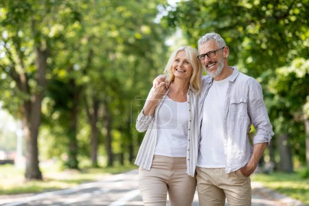 Retrato de una hermosa pareja de ancianos caminando juntos en el parque de verano, cónyuges maduros felices abrazando y sonriendo, hombre y mujer mayores relajándose afuera, disfrutando del ocio después de la jubilación, espacio de copia