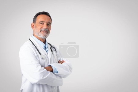 Photo for Smiling confident caucasian senior doctor therapist in white coat with crossed arms, enjoy work, isolated on gray background, studio. Medical help, health care, professional occupation - Royalty Free Image