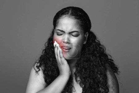 Foto de Mujer gordita latina triste presionando de la mano a la mejilla, que sufre de dolor de dientes, foto en blanco y negro. Problemas de salud, caries, dolor de muelas - Imagen libre de derechos