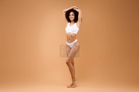 Photo for Fit slim latin lady with perfect body figure posing in underwear over brown studio background, full length shot, copy space. Female model showing her curves - Royalty Free Image