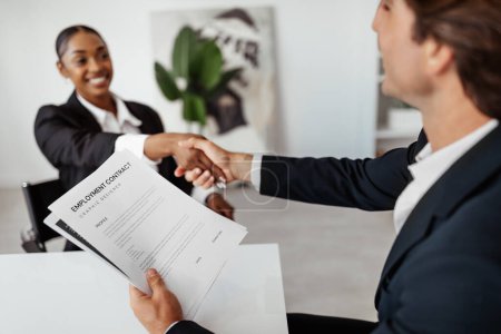 Photo for Successful job interview. Hired black female candidate seals the deal with the HR team recruiter by handshaking after signing employment contract - Royalty Free Image