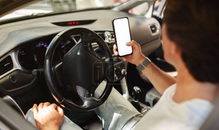 Foto de Hombre conductor sentado en frente sentarse en el coche, sosteniendo el teléfono móvil con pantalla blanca en blanco, mapa de navegación GPS, tipo irreconocible comprobar el destino de la ubicación, utilizando la aplicación, viajando solo en coche - Imagen libre de derechos