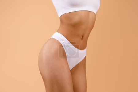 Photo for Body slimming concept. Lady with slim sporty figure in white underwear, woman torso with flat abdomen over brown studio background, cropped - Royalty Free Image