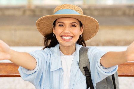 Foto de Feliz mujer europea bastante joven en sombrero con mochila hace selfie, disfruta de viaje, al aire libre. Emociones turísticas para blog, redes sociales, viajes, estilo de vida activo en verano, fin de semana - Imagen libre de derechos