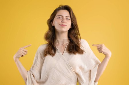 Photo for Happy confident young caucasian woman in casual pointing fingers at herself, isolated on yellow studio background. Pride, self-confidence, recommendation, ad and offer, human emotions - Royalty Free Image