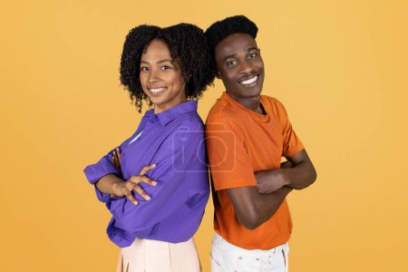 Photo for Cheerful confident millennial black woman and man in casual with crossed arms on chest, isolated on yellow studio background. Lifestyle, team, ad and offer, relationships, love - Royalty Free Image
