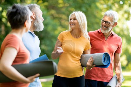 Photo for Group of happy senior people talking to each other after exercising at park, active elderly men and women chatting and laughing, cheerful mature friends relaxing after yoga outside, closeup - Royalty Free Image
