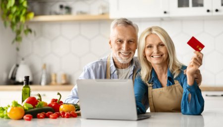 Téléchargez les photos : Online Shopping. Elderly Spouses Posing With Laptop And Credit Card In Kitchen, Smiling Senior Couple Making Payments In Internet Or Ordering Groceries Delivery, Enjoying E-Commerce, Closeup - en image libre de droit