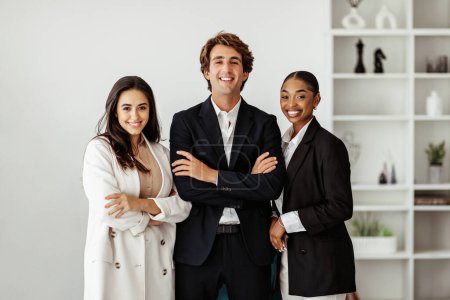 Photo for Business company managers. Three happy multiracial business professionals posing in office interior, businessman and businesswomen looking at camera advertising career offer - Royalty Free Image